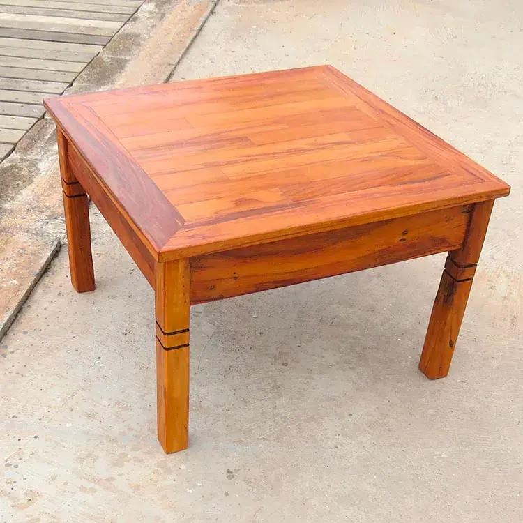 Vista lateral da mesa de centro quadrada em peroba rosa, com dimensões de 65cm x 65cm e altura de 38cm.